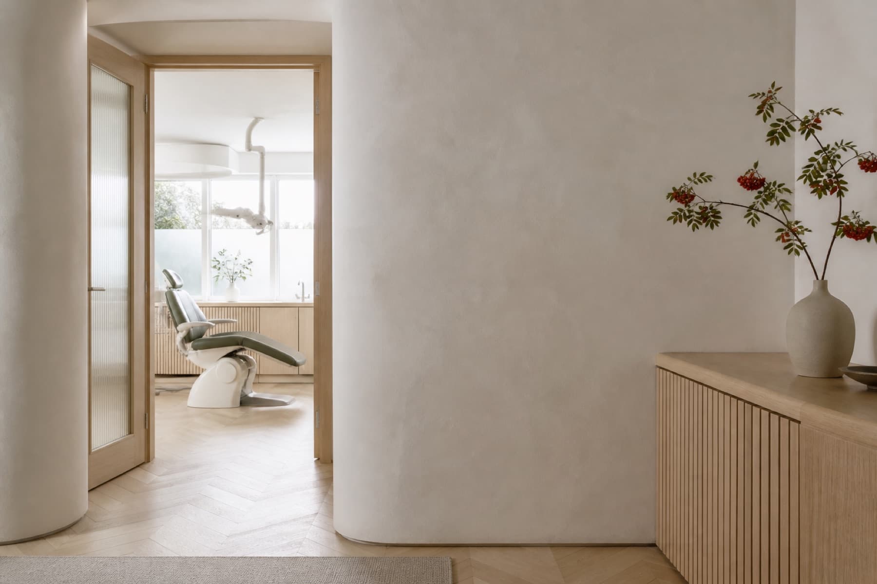 Fictional calm dental practice with pale oak and a treatment room doorway